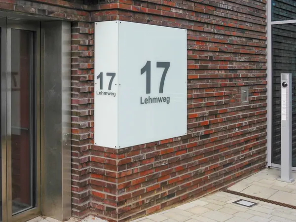 Schilder in Gewebeobjekten als Wegweiser für die Besucher. ESG Glasscheiben mit Folienbeschriftung als Kennzeichnung des Hauseingangs.