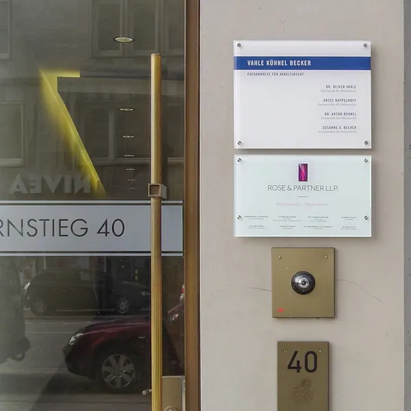 Schilder in Gewebeobjekten als Wegweiser für die Besucher. Glasscheiben montiert mit Edelstahl-Abstandhaltern montiert an einem Hamburger Bürohaus