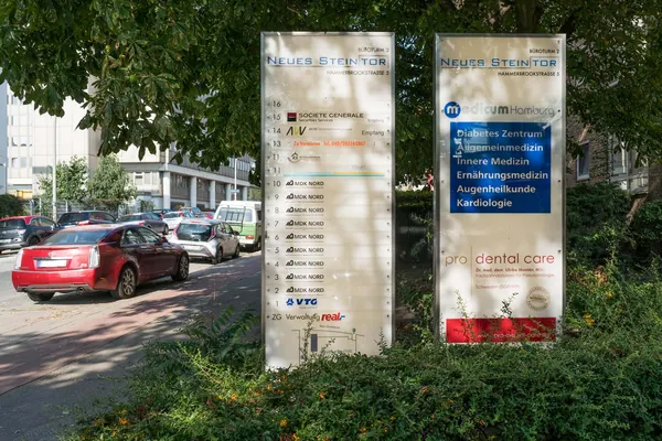 Standpylone aus Edelstahl mit eingesetzten Plexiglasscheiben. Mieterbeschriftung als Folientext