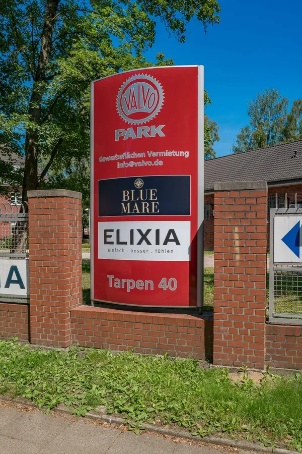 Das Foto zeigt einen Werbepylon an der Zufahrt zum Gewerbepark Valvo Park. Die Pylone sind aus Aluminum gefertigt mit einer Front aus Plexiglas.