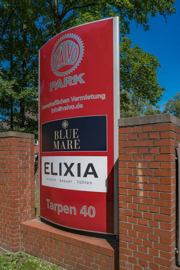 Das Foto zeigt einen Werbepylon an der Zufahrt zum Gewerbepark Valvo Park. Die Pylone sind aus Aluminum gefertigt mit einer Front aus Plexiglas.
