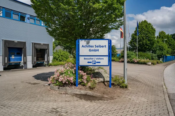 Das Foto zeigt ein Standschild gefertigt aus Aluminium und ESG-Glasscheiben. Das Firmenschild zeigt den Namen und einen Hinweis für die Kundenparkplätze.