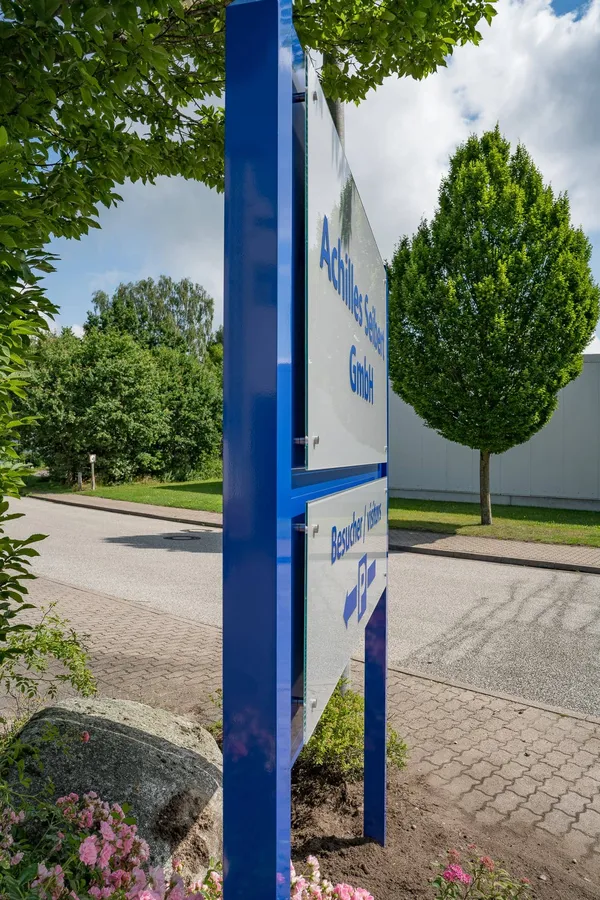 Das Foto zeigt ein Standschild gefertigt aus Aluminium und ESG-Glasscheiben. Das Firmenschild zeigt den Namen und einen Hinweis für die Kundenparkplätze.
