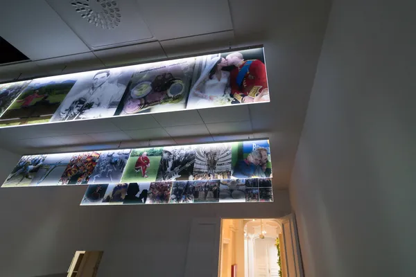 Das Foto zeigt einen LED Lichtfluter von der Decke abgehängt. Auf den leuchtenden Acrylglasscheiben wurden Bilder auf selbstklebender Folie verklebt.