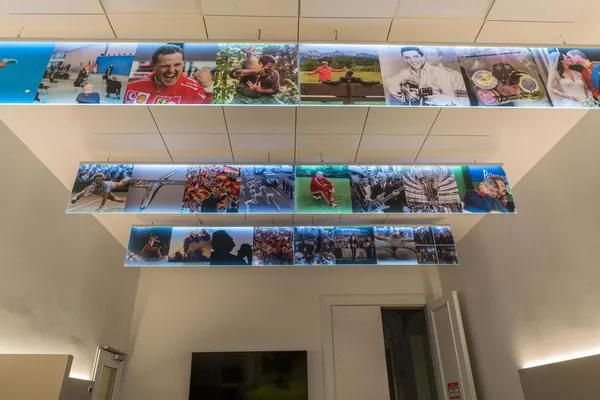 Das Foto zeigt einen LED Lichtfluter von der Decke abgehängt. Auf den leuchtenden Acrylglasscheiben wurden Bilder auf selbstklebender Folie verklebt.