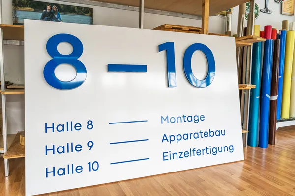 LED Buchstaben montiert auf eine lackierte Aluminiumblende. Die LED Buchstaben leuchten zur Seite und die Front ist blau lackiert.
