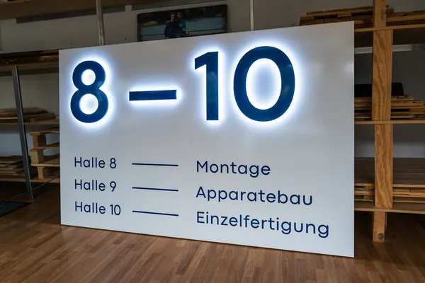 LED Buchstaben montiert auf eine lackierte Aluminiumblende. Die LED Buchstaben leuchten zur Seite und die Front ist blau lackiert.