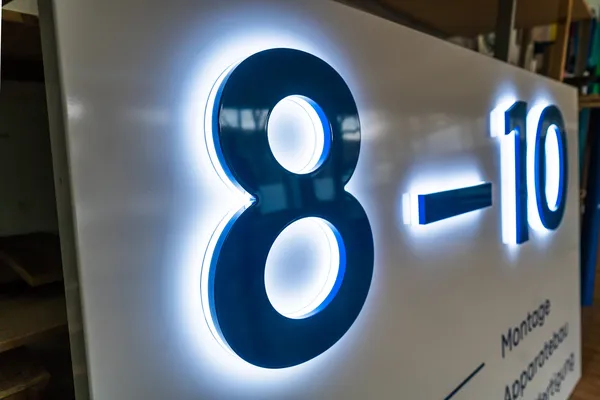 LED Buchstaben montiert auf eine lackierte Aluminiumblende. Die LED Buchstaben leuchten zur Seite und die Front ist blau lackiert.