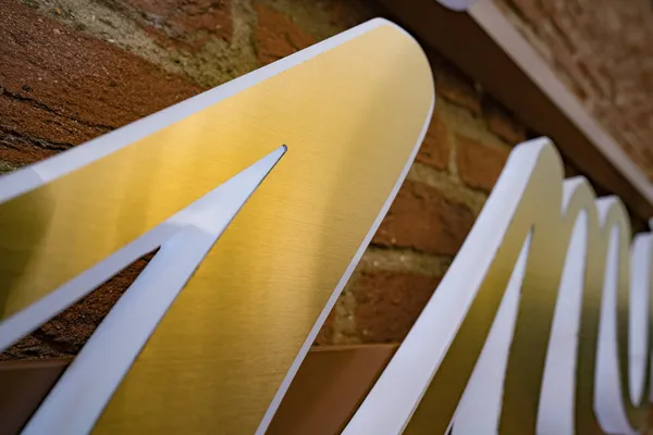 3D Buchstaben aus LED Vollplexi Buchstaben mit gold gebürstetem V2A belegt. Eine Aussenwerbung für Heimatglück Immobilien in Lübeck.