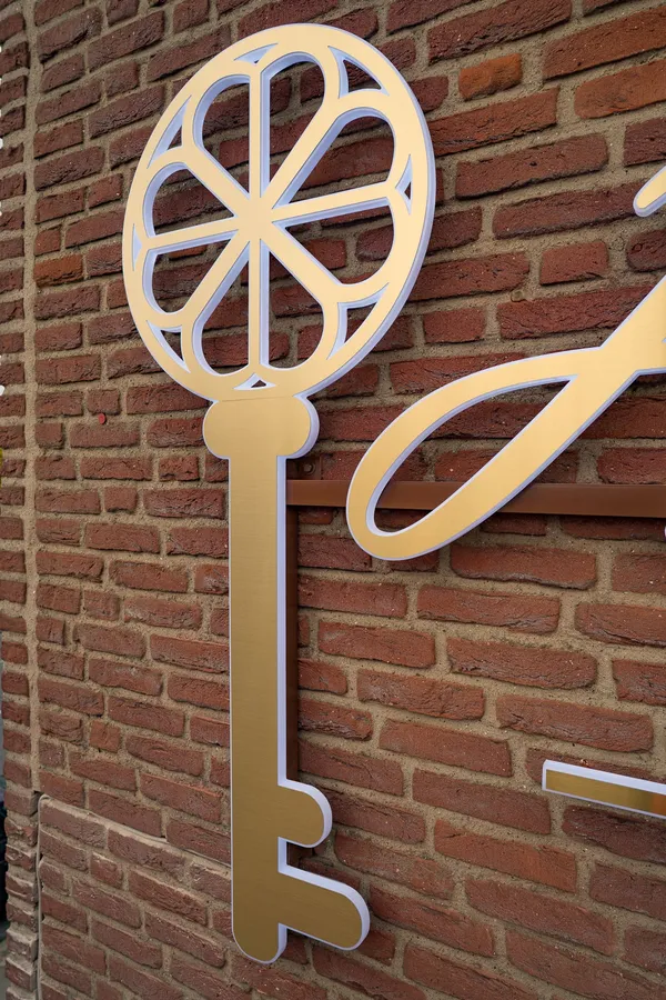 3D Buchstaben aus LED Vollplexi Buchstaben mit gold gebürstetem V2A belegt. Eine Aussenwerbung für Heimatglück Immobilien in Lübeck.