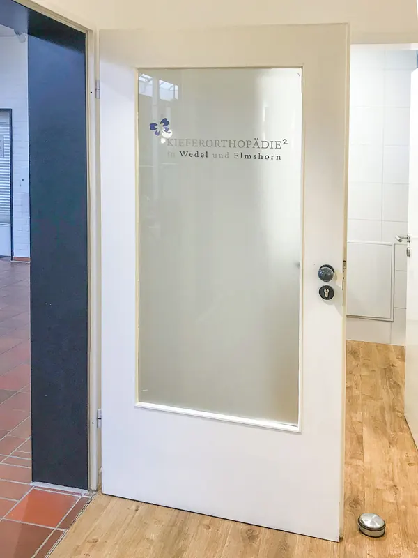 Milchglasfolie auf einer Tür als Sichtschutz für eine Zahnarztpraxis. Das Logo ist mit computergeschnittenen Folien aufgeklebt.